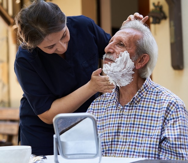 a caregiver shaving an elderly man
